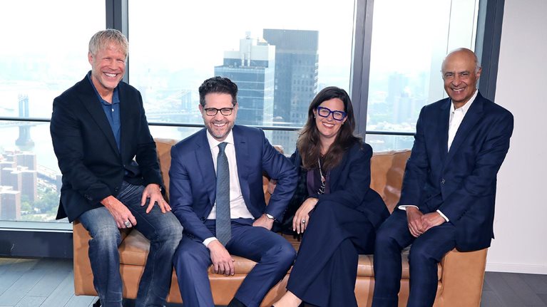 Photograph of Carolyn Dewar, Kurt Strovink, Scott Keller, and Vik Malhotra sitting together in a modern office.