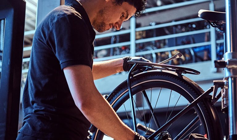 Attractive mechanic is fixing customer's bicycle at his own workshop.