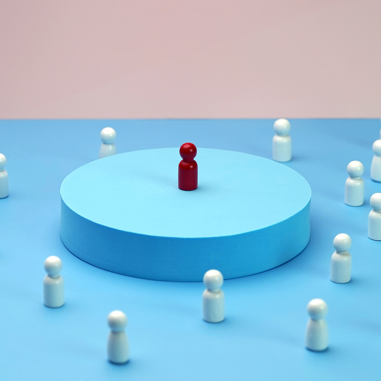 Visionary leader symbol with unique and creative solution. Single wooden block doll standing on elevated platform, other wooden block dolls gathered around listening.