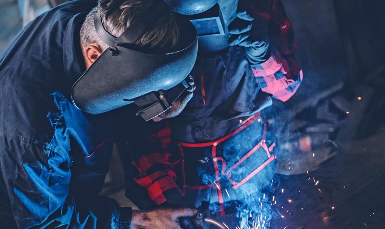 Man and woman welding together in workshop