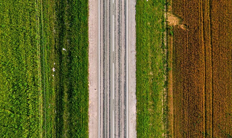 Aerial shot of an empty highway on a green and brownfield