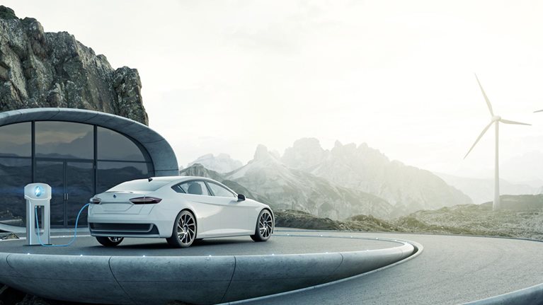 Electric car charging at modern architecture with wind turbines