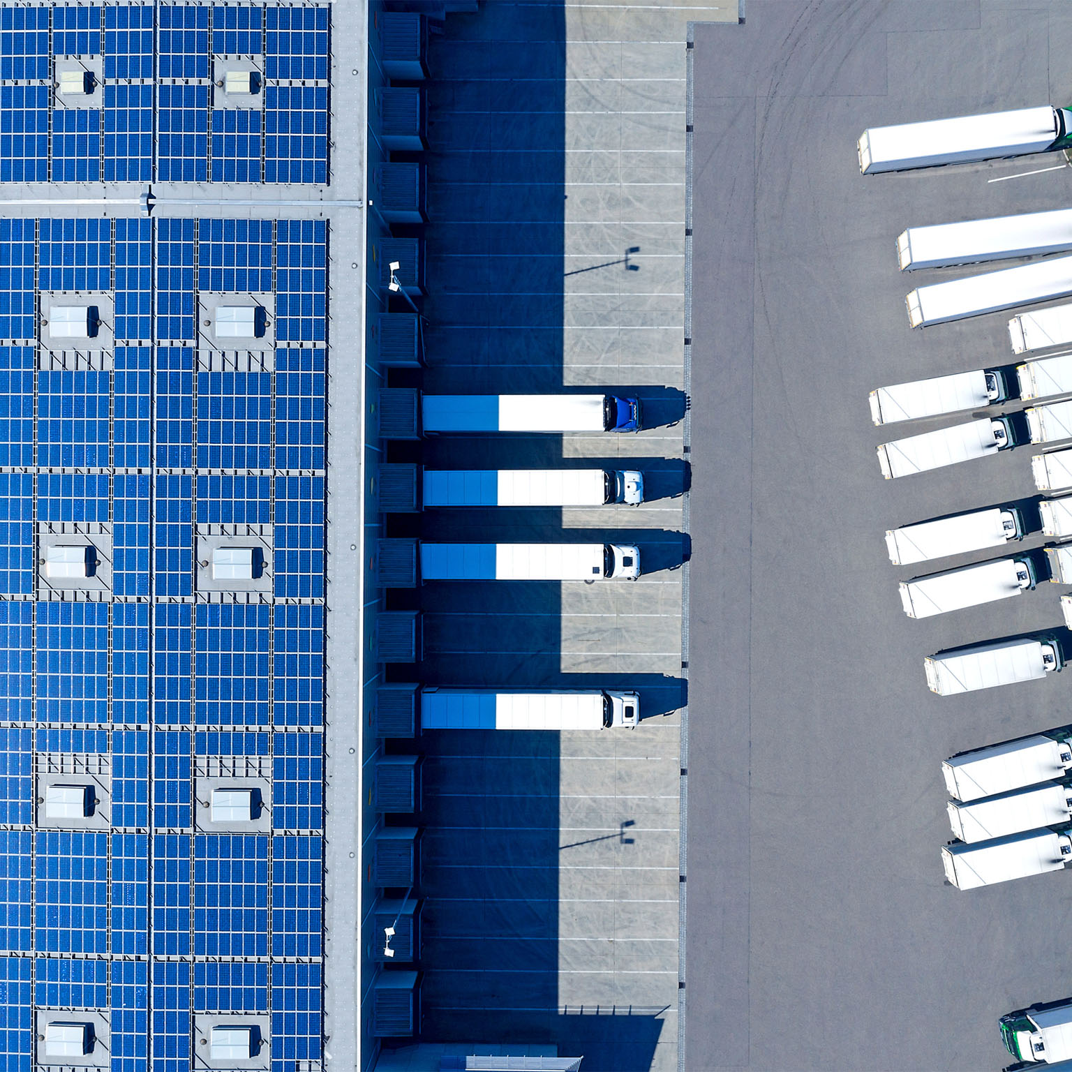 Aerial view of trucks loading at distribution warehouse with solar photovoltaic panels