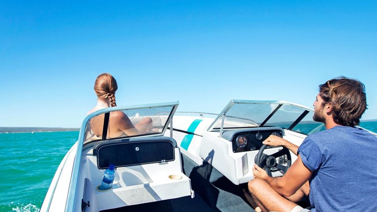 Man steering boat on water with girlfriend