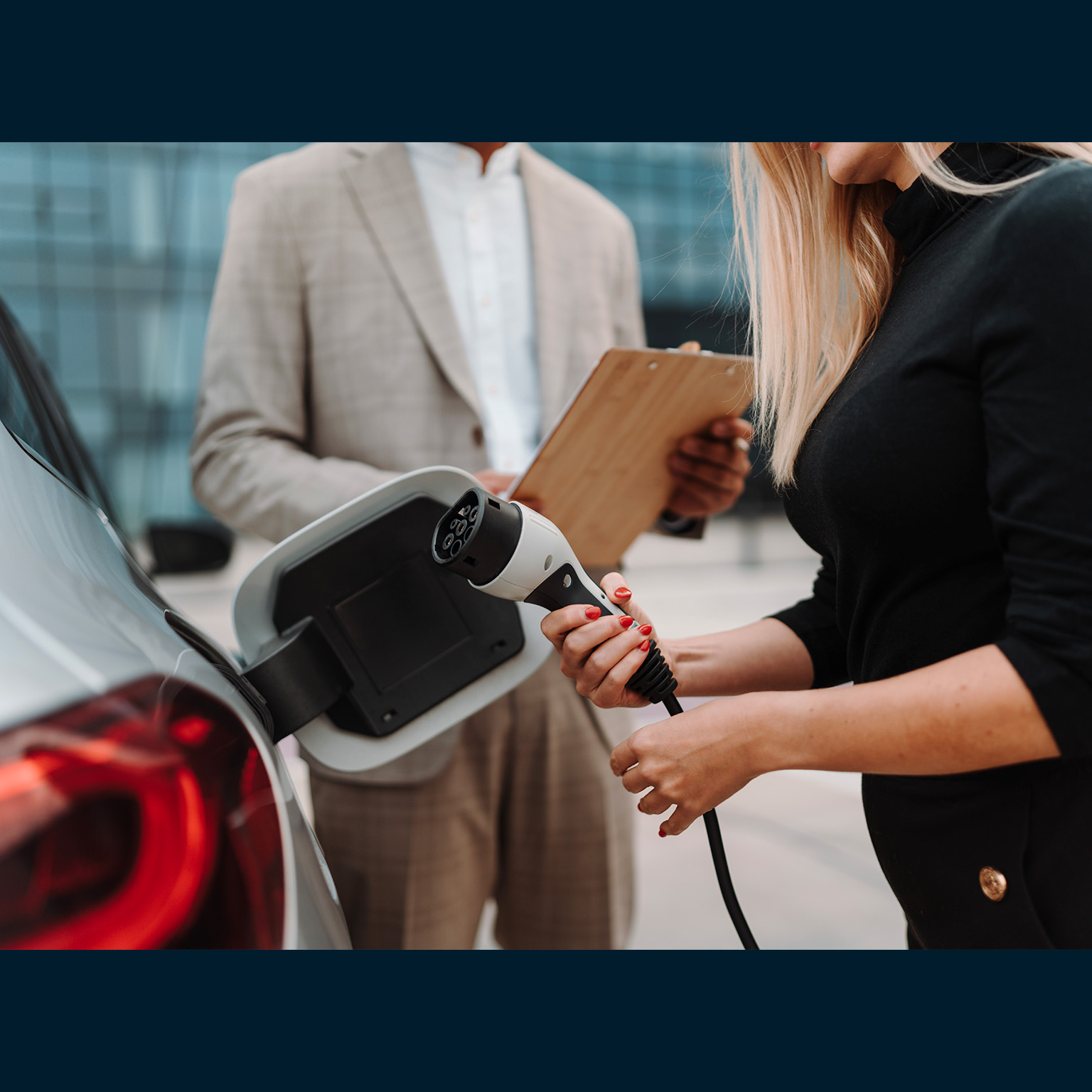 Young salesman showing charging electric car. - stock photo