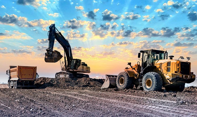 Excavators working on construction site at sunset