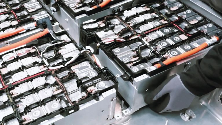Close-up of two mechanics repairing the battery of an electric car in a car workshop