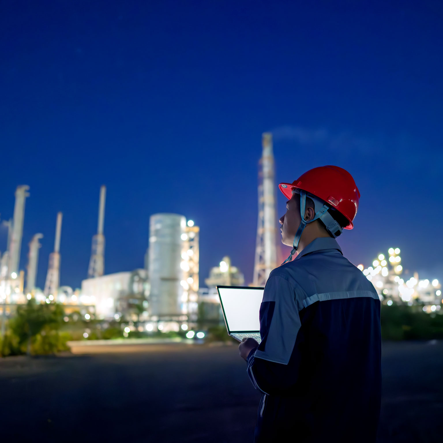 Chemical plant engineer using laptop at night