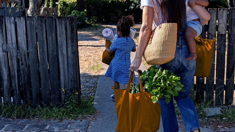 Young Australian family carries the shopping in together and hugs after being at school and work