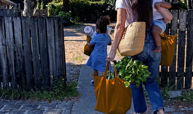 Young Australian family carries the shopping in together and hugs after being at school and work