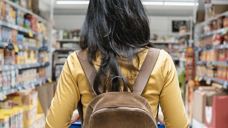 Woman with backpack pushing shopping cart