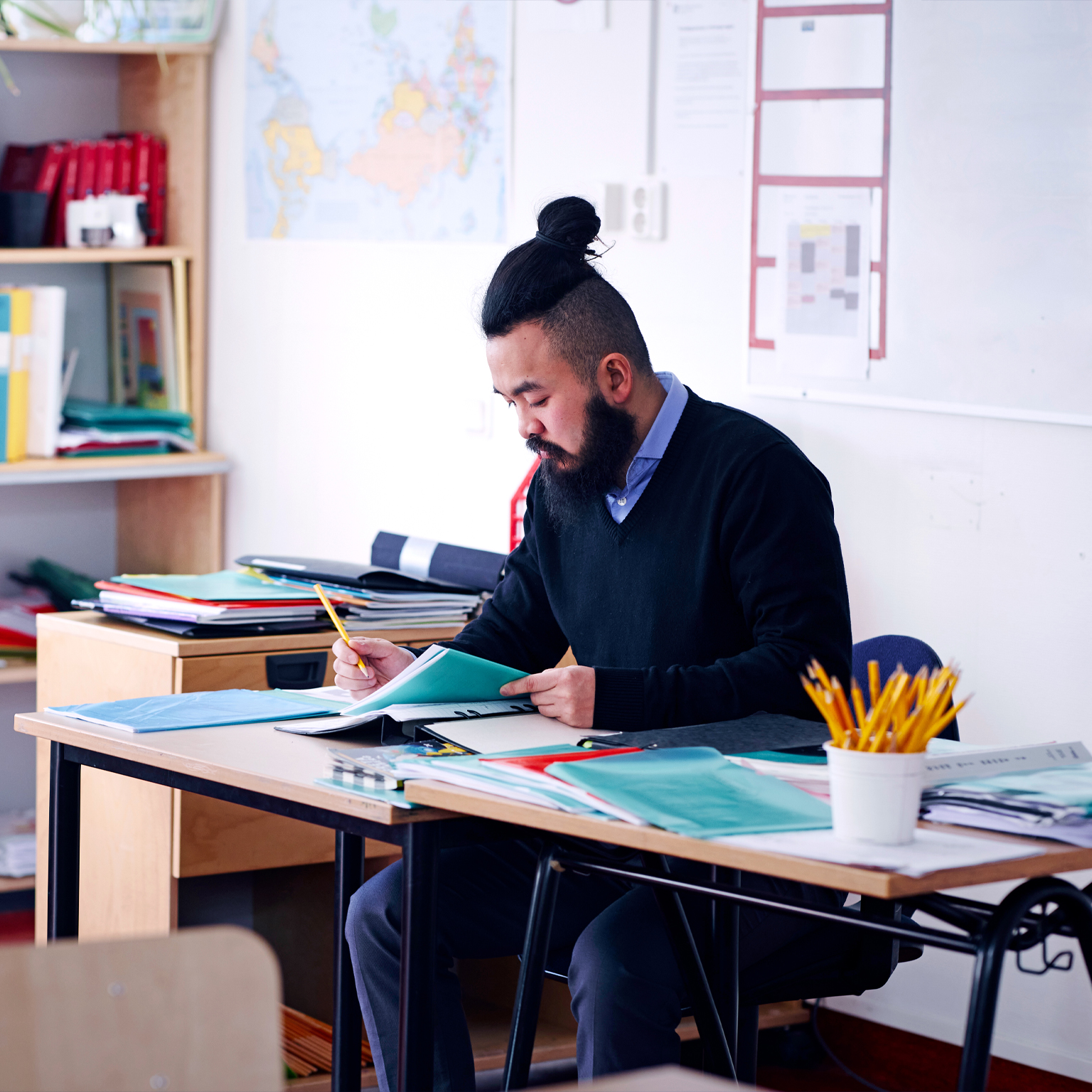 A teacher sitting at his desk looking at a booklet