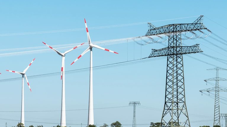 Grassy landscape with wind turbines, power lines, and solar panels.