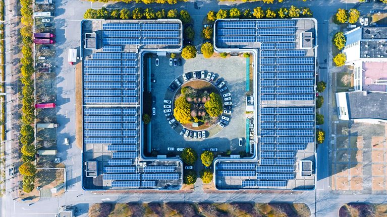 Aerial view of solar panels covering the top of a modern office building.