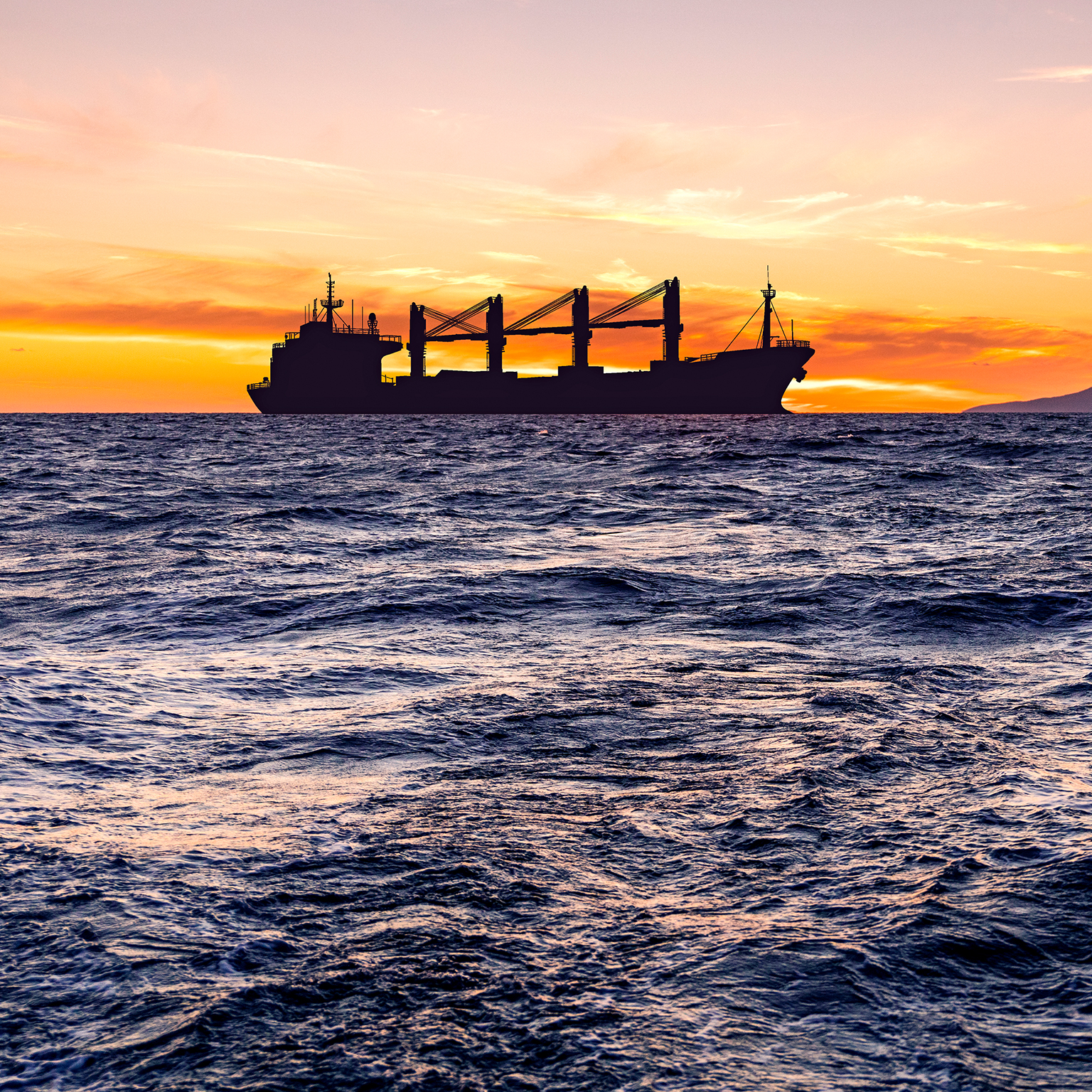 Cargo ship with grain at sea at sunset.