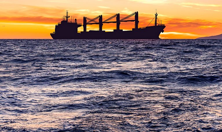 Cargo ship with grain at sea at sunset.