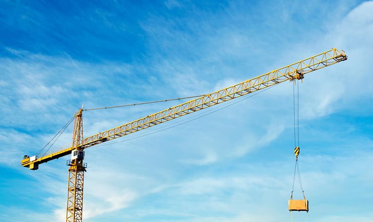 Crane at construction site against cloudy sky