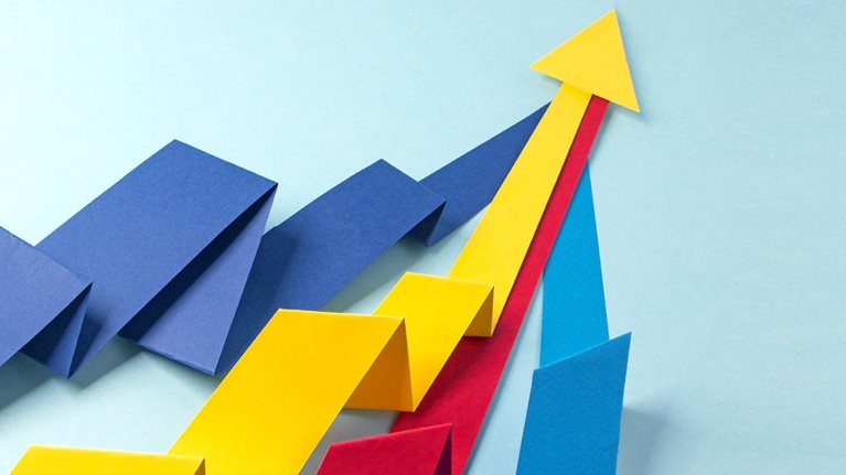 Red, blue, yellow paper arrows folded to appear like three-dimensional graphs merging at the top, with the yellow arrow head visible over others.