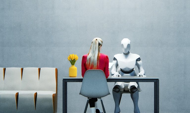 A woman in a red jacket sitting at a table across from a humanoid robot in a sparsely decorated office space.