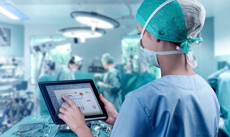 Female surgeon using digital tablet to command artificial heart in operation room.