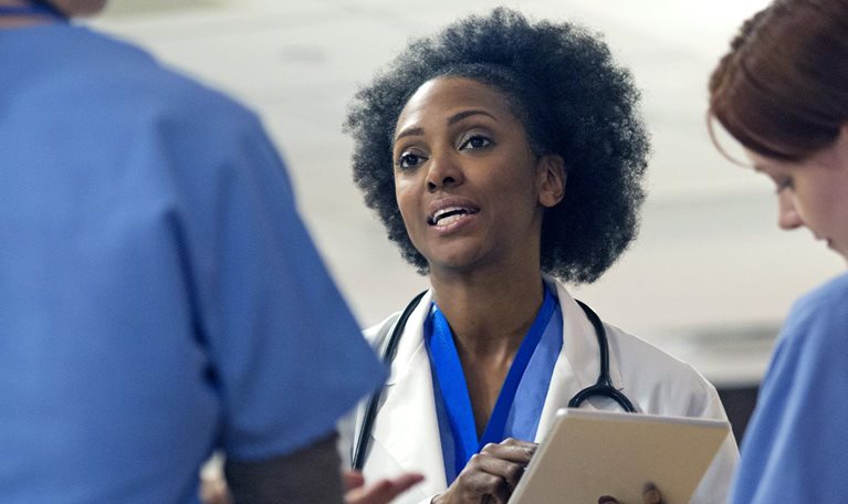 Image of a medical team with women in it having a stand-up meeting at a hospital.