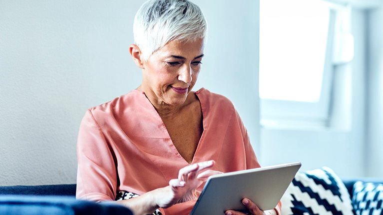 Older Caucasian woman using digital tablet on sofa