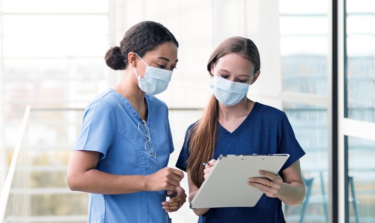 Two female surgeons confer before seeing patients in the hospital