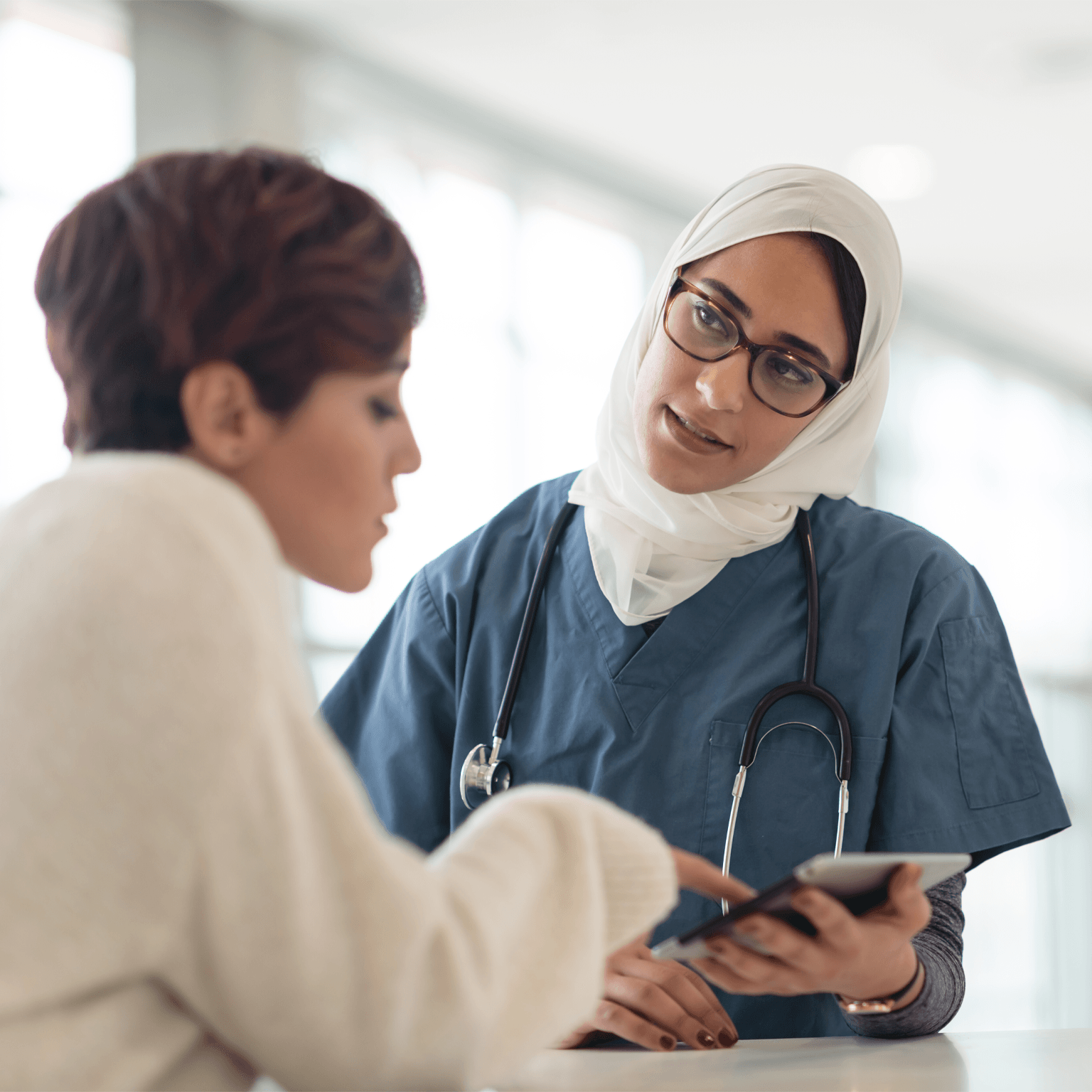 Saudi Arabian nurse with tablet helping patient