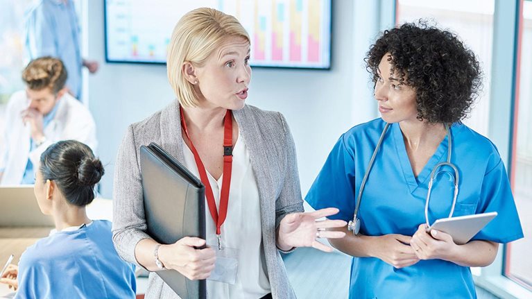 A businesswoman meets with a doctor prior to sitting at a boardroom meeting in a hospital