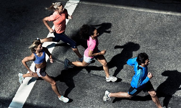 Overhead shot of urban runners going down street. - stock photo