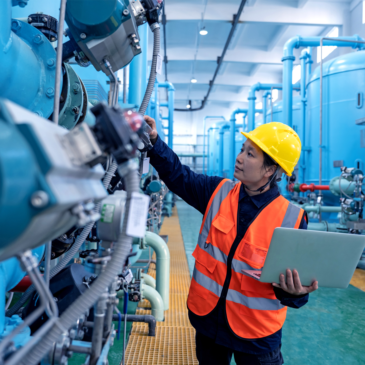 A female engineer works in a chemical plant using a laptop computer - stock photo