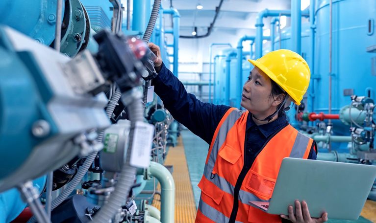A female engineer works in a chemical plant using a laptop computer - stock photo