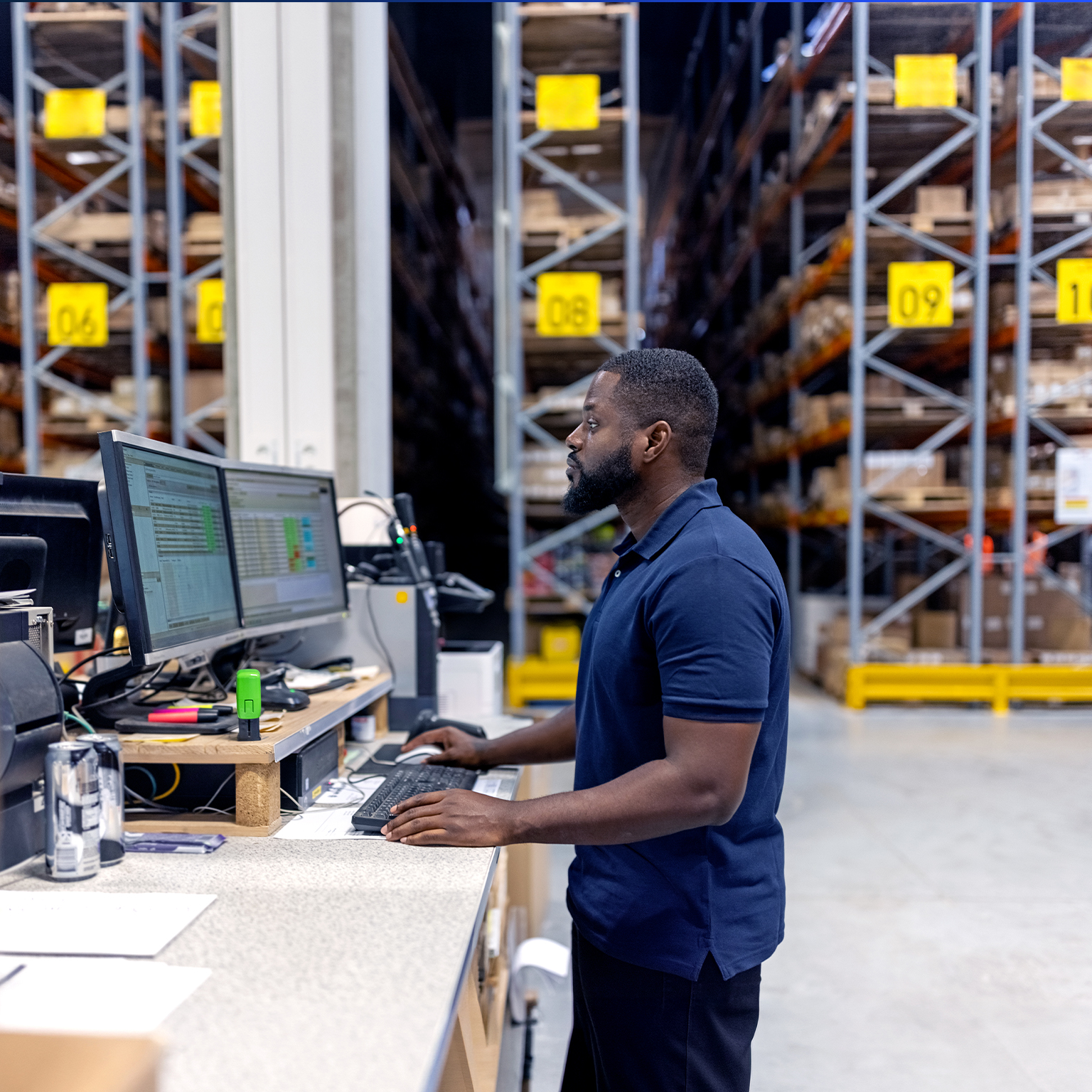 Man working on computer in large factory warehouse