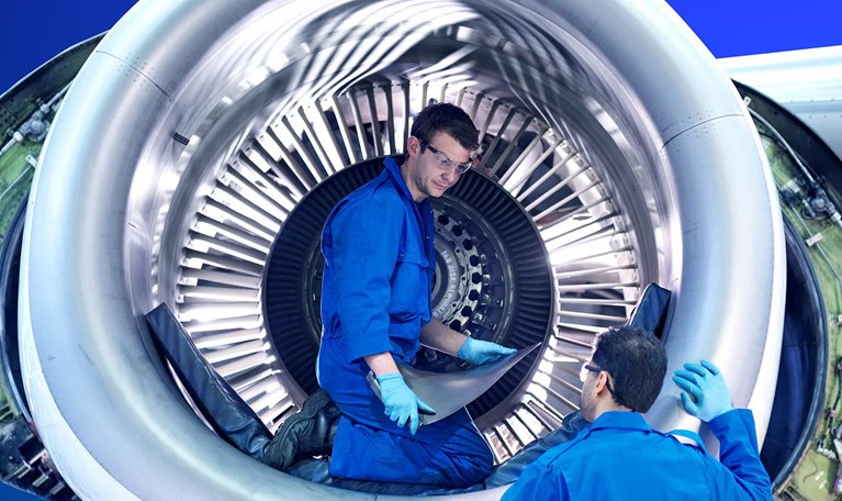 Engineers working with jet engine turbine blade in aircraft maintenance factory