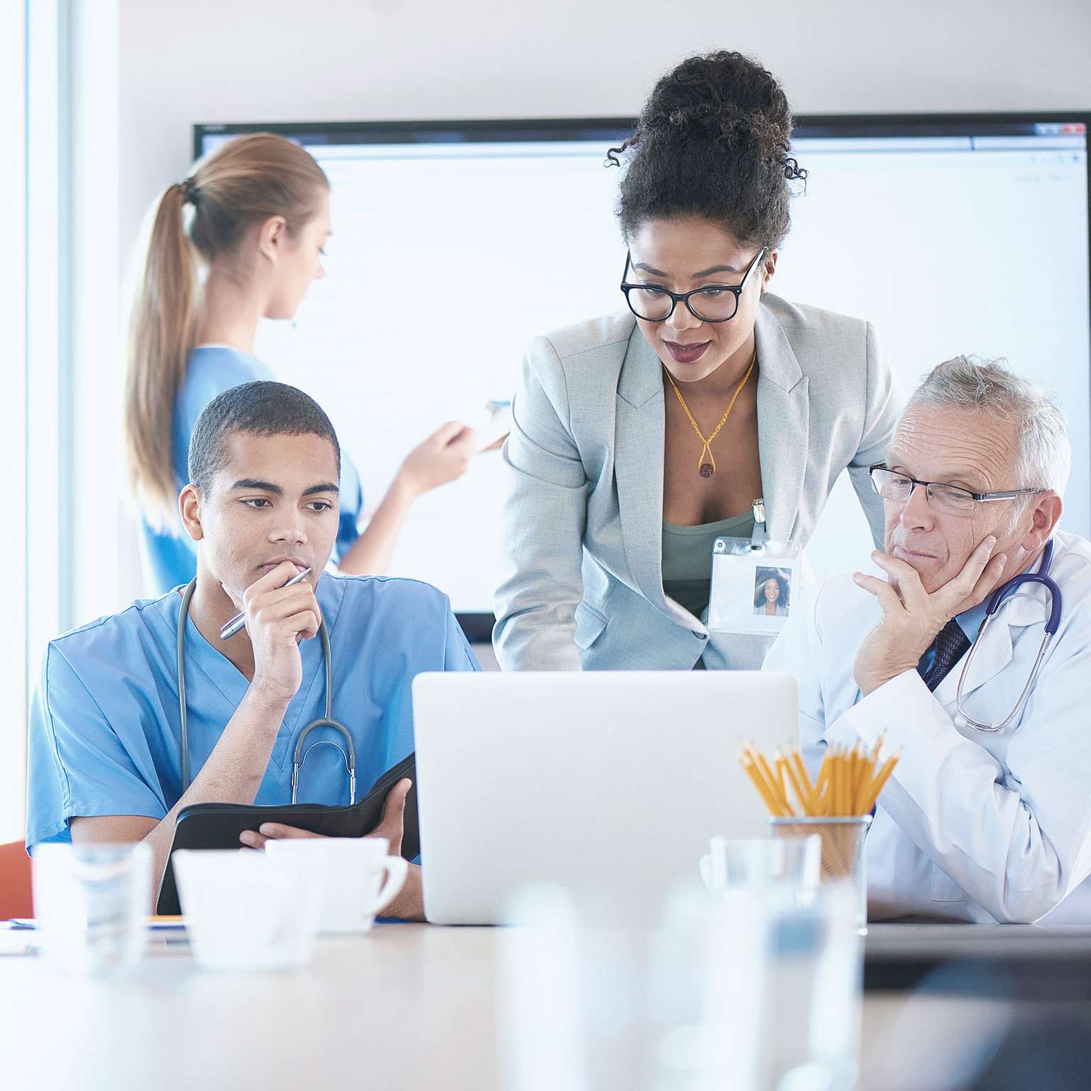 A medical team are discussing something around a boardroom table.