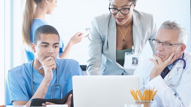 A medical team are discussing something around a boardroom table.
