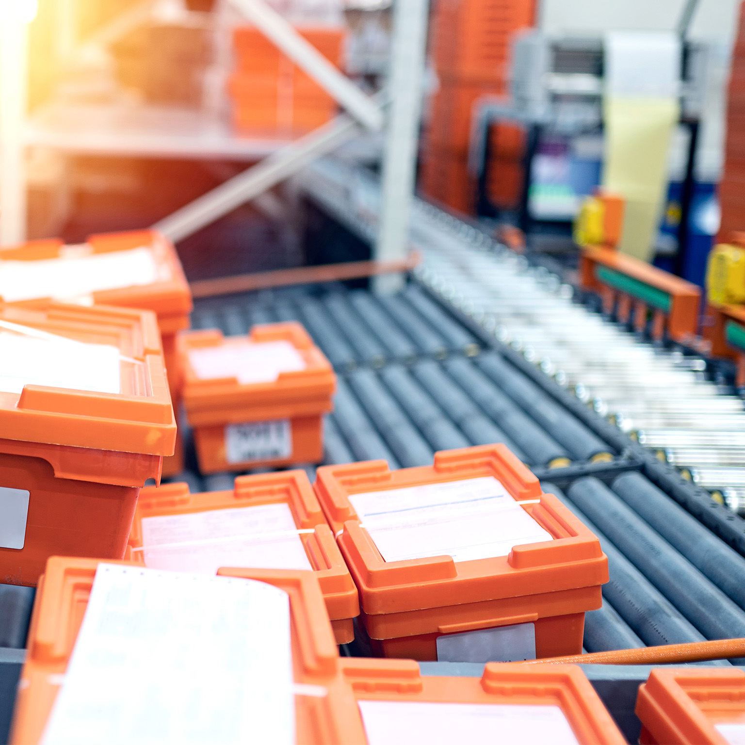 Warehouse conveyor belt with orange crates that are being packed with medicine