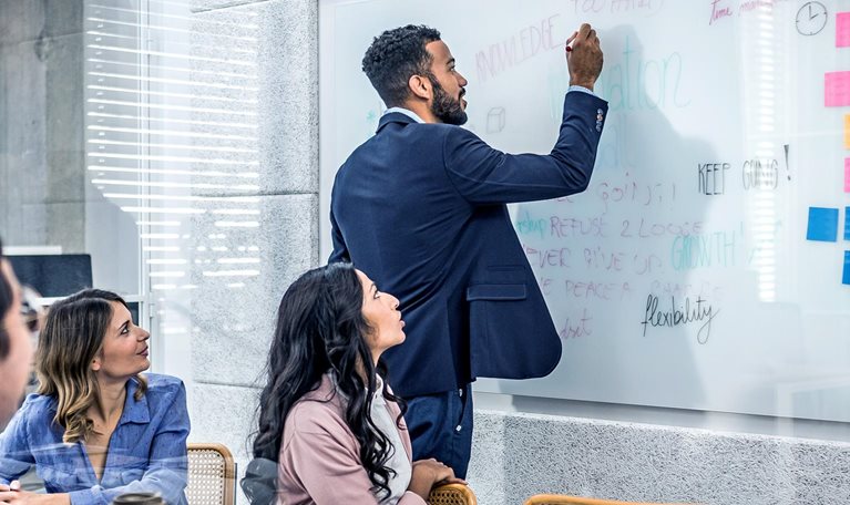 Coworkers writing on whiteboard