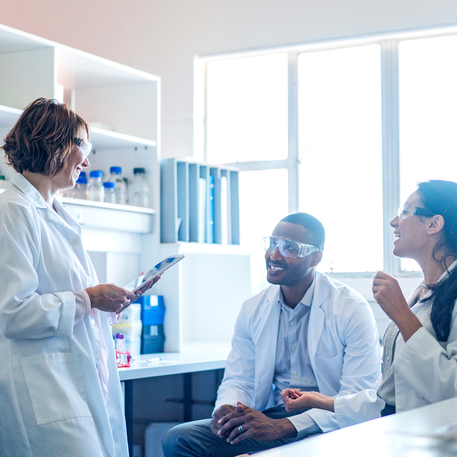 Chemist using tablet PC while talking to coworkers