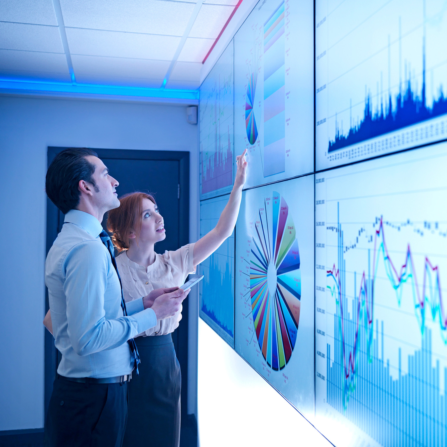 Business colleagues studying graphs on screen in meeting room