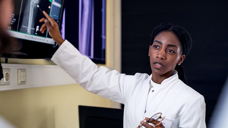Female surgeon discussing patient's scan and diagnosis with colleagues