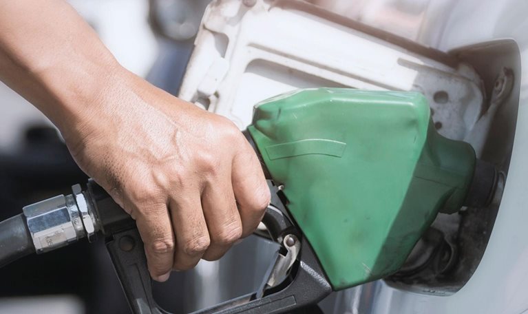 Hand holds fuel nozzle to add fuel in car
