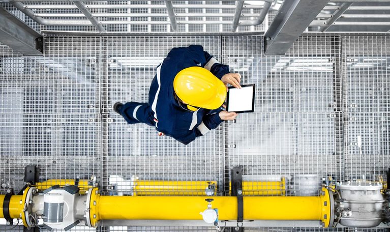 Top view of petroleum refinery worker walking by gas pipes and checking production.