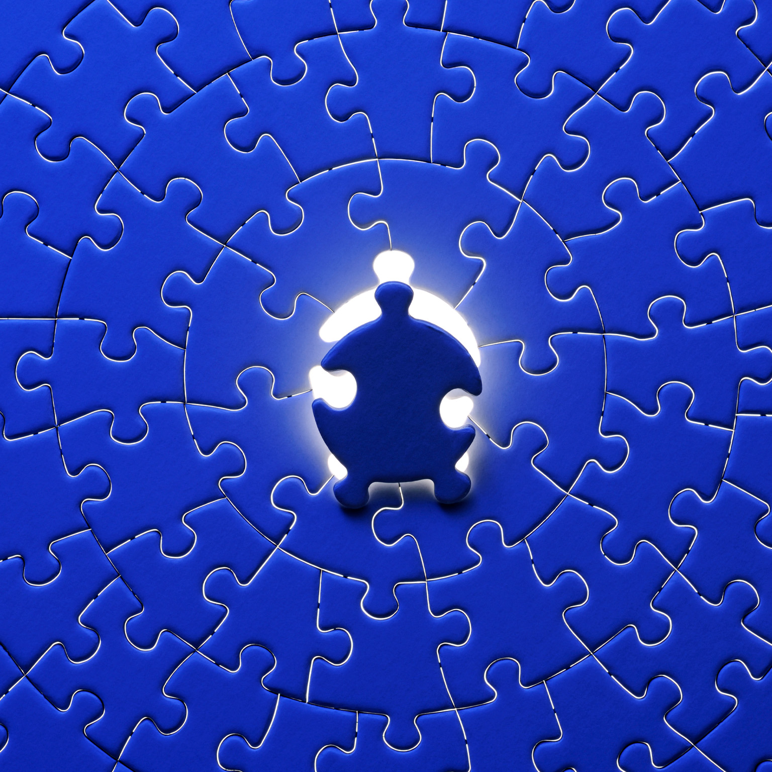 Blue final piece of the jigsaw with light from behind.