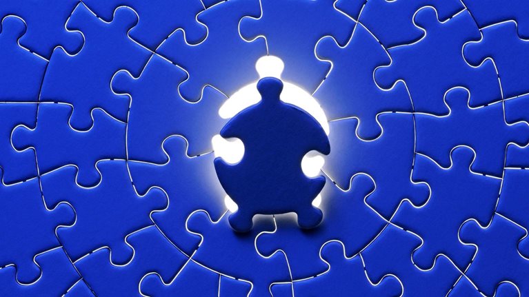 Blue final piece of the jigsaw with light from behind.