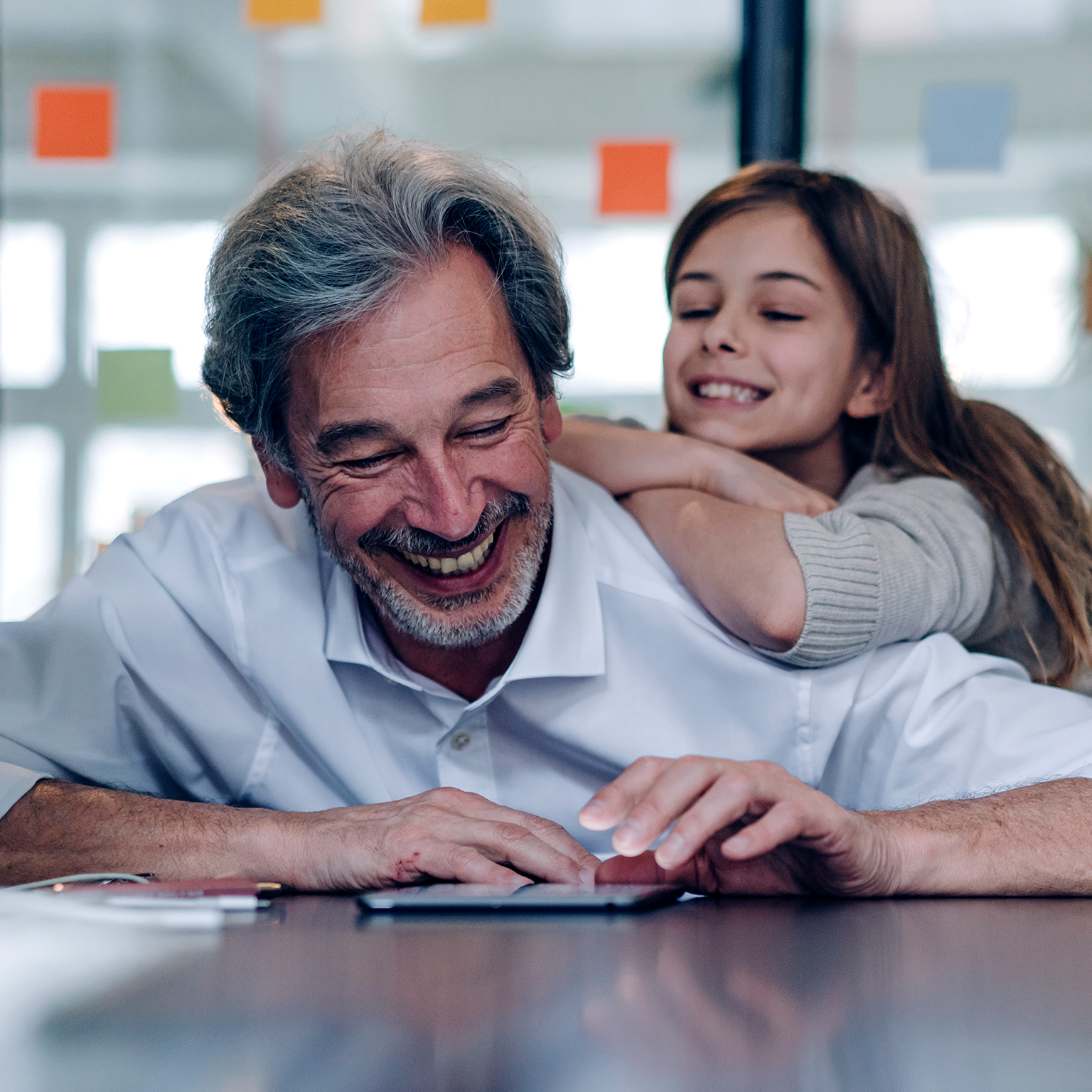 Happy senior businessman and girl looking at tablet in office.