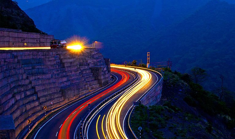 Red and white light trails on road at twilight in India mountain range