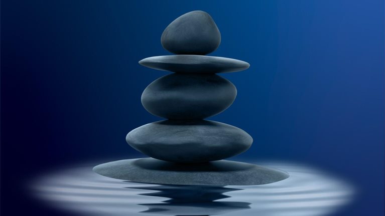 Stacked black zen stones in shallow water