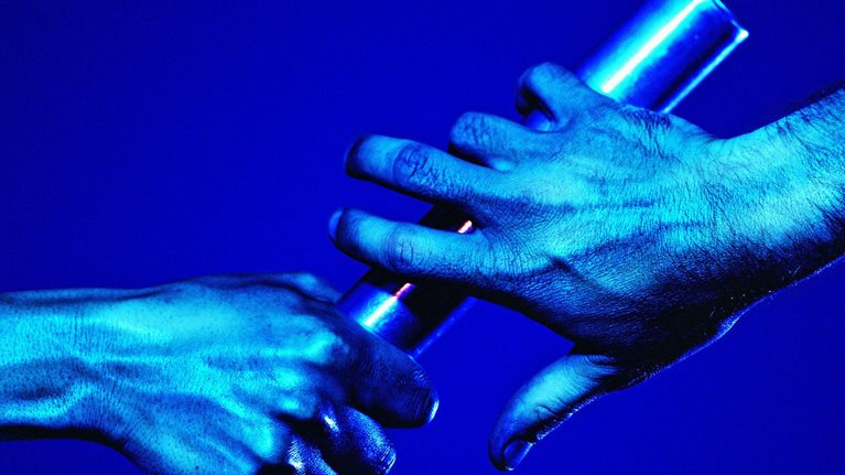 One hand passing a baton to the other