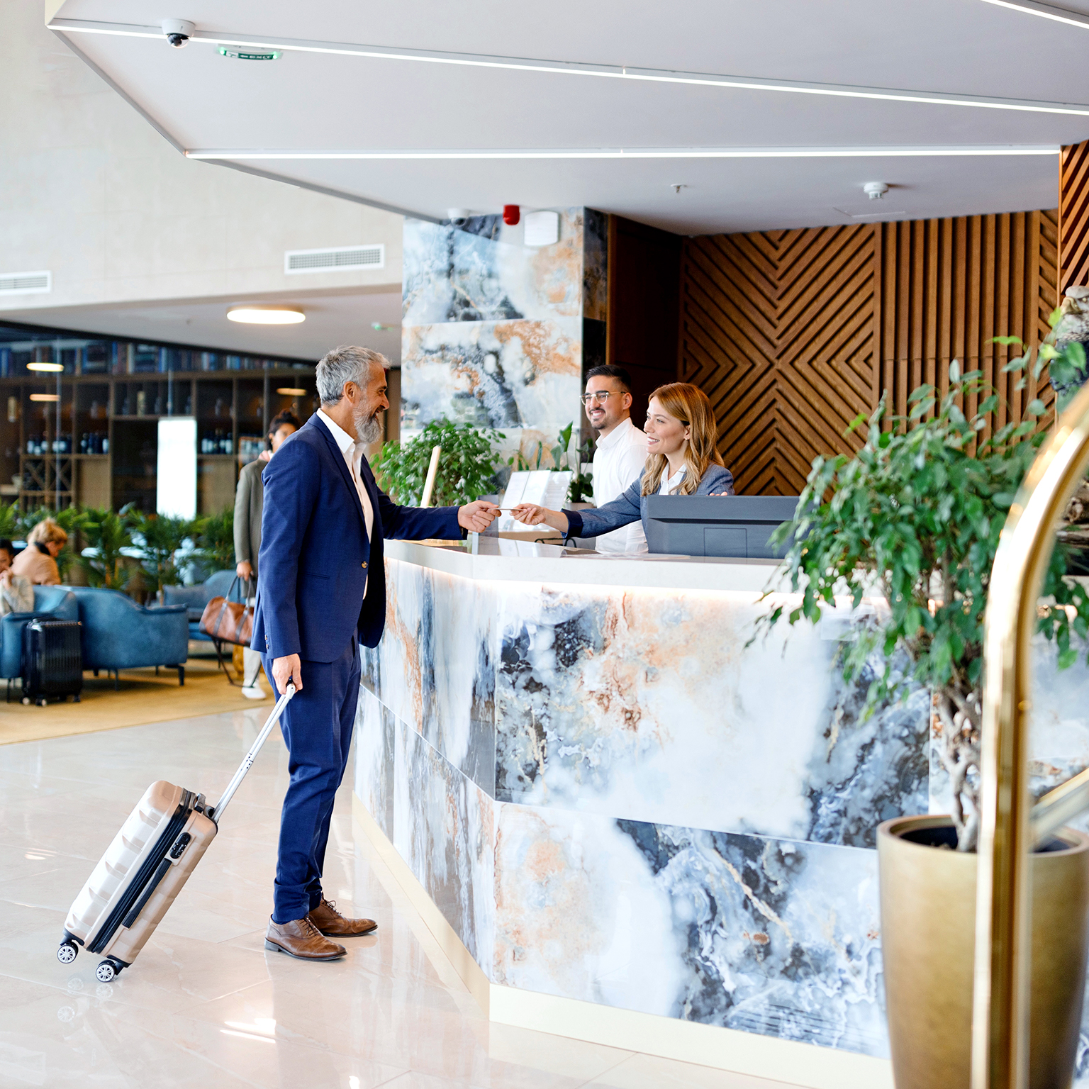  Elegantly dressed businessman talking with a receptionist while checking out from the hotel